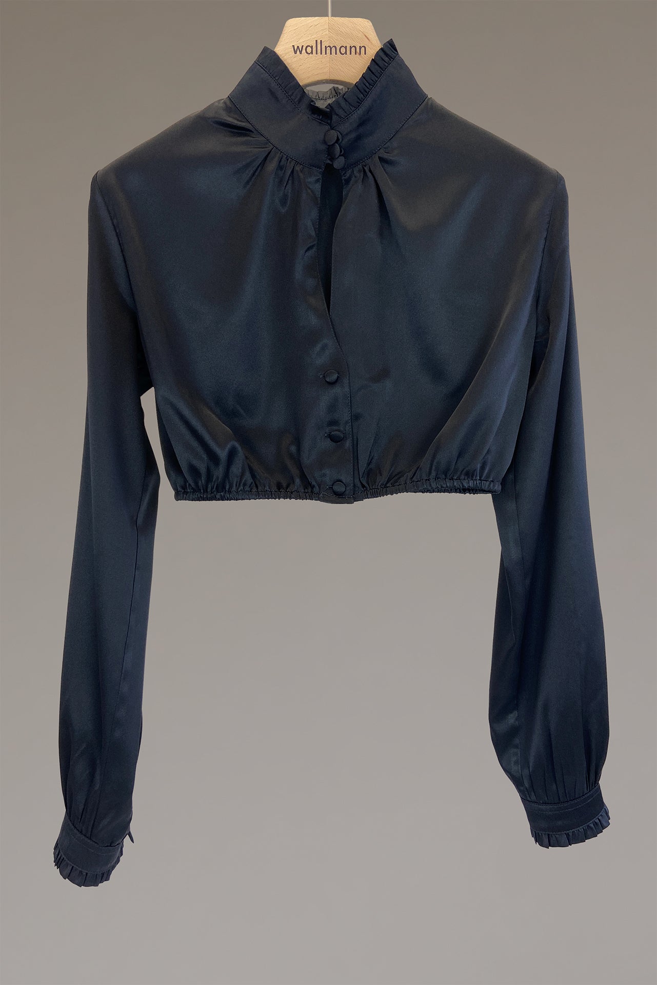 schwarze seidendirndlbluse mit breitem stehkragen mit rueschenabschluss, gezuegelter langarm mit manschette und rueschenabschluss, ueberzogene knoepfe, um den stehkragen zu schließen, ausschnittschlitzchen vorne, leiste mit ueberzogenen knoepfe und leicht gezuegelt am halsausschnitt, anliegend an aermel und oberkoerper, gummizug an taille für den perfekten halt, ideale passform, wallmann